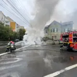 Pompieri români care intervin la locul unui accident rutier unde o mașină a luat foc sau scoate fum dens