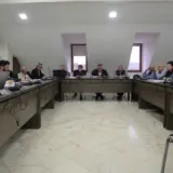 A group of people sitting around a large U-shaped desk during a local administration meeting