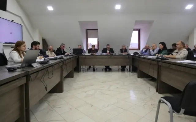 A group of people sitting around a large U-shaped desk during a local administration meeting