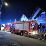 O fotografie de noapte care prezintă o autospecială de pompieri (ISU) și o ambulanță SMURD parcate pe o stradă rezidențială în fața unor case